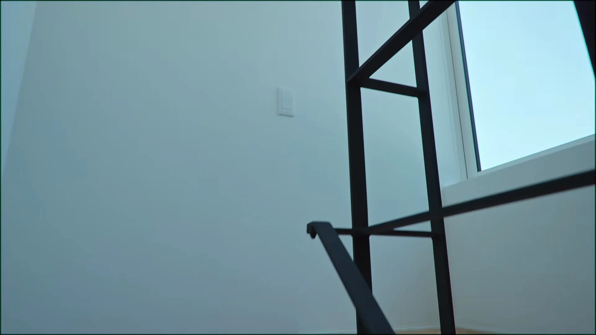 上の部屋へ上がる階段の黒い手すりと、その先の窓